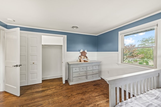 bedroom with visible vents, wainscoting, dark wood-style floors, crown molding, and a closet