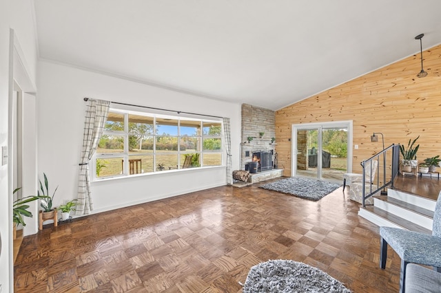 living area featuring plenty of natural light, wood walls, a stone fireplace, and stairs