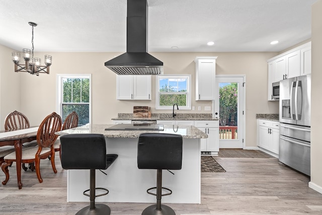 kitchen featuring stainless steel appliances, white cabinets, island exhaust hood, and a kitchen island