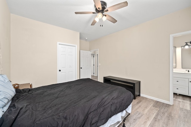 bedroom featuring ensuite bathroom, ceiling fan, light wood-style flooring, a sink, and baseboards