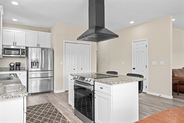 kitchen with light wood-type flooring, island exhaust hood, white cabinetry, and stainless steel appliances