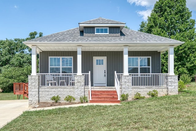 view of front of property featuring covered porch, a front lawn, board and batten siding, and roof with shingles