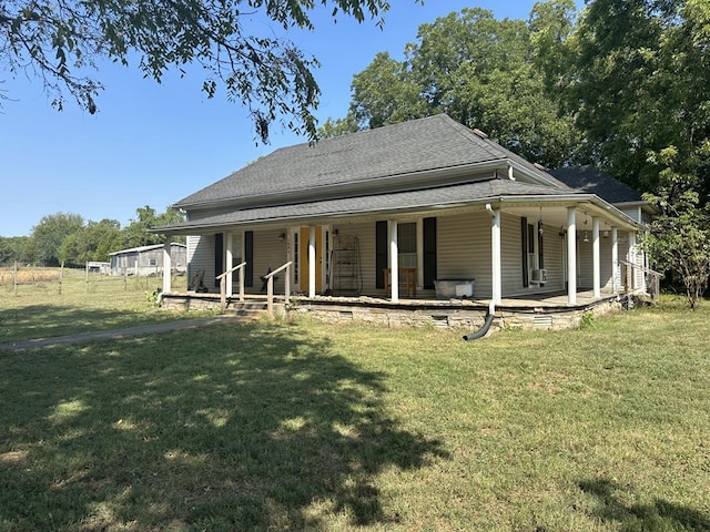 rear view of property with a porch, roof with shingles, and a yard