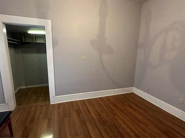 unfurnished bedroom featuring a closet, wood finished floors, and baseboards