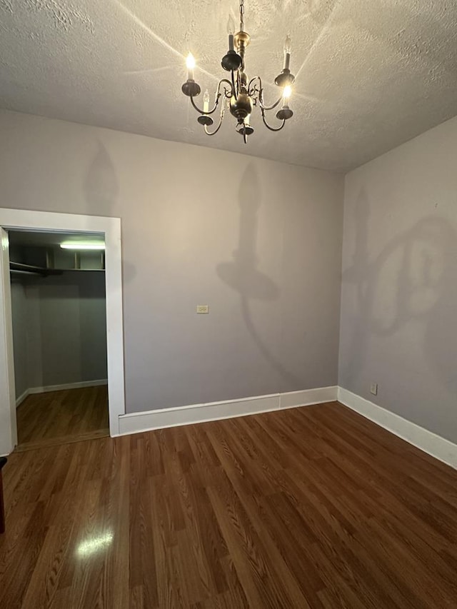 interior space featuring a textured ceiling, baseboards, dark wood-style flooring, and a notable chandelier