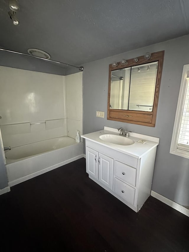 bathroom with shower / bathing tub combination, a textured ceiling, vanity, wood finished floors, and baseboards