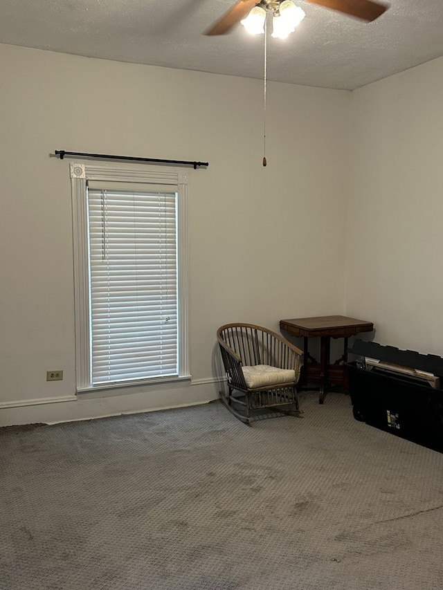 living area with a textured ceiling, carpet floors, a ceiling fan, and baseboards