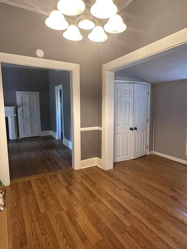 unfurnished dining area with baseboards, a chandelier, and dark wood-style flooring