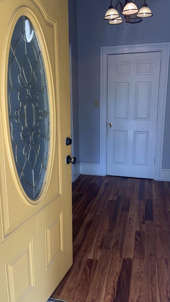 foyer with a notable chandelier, baseboards, and dark wood-type flooring