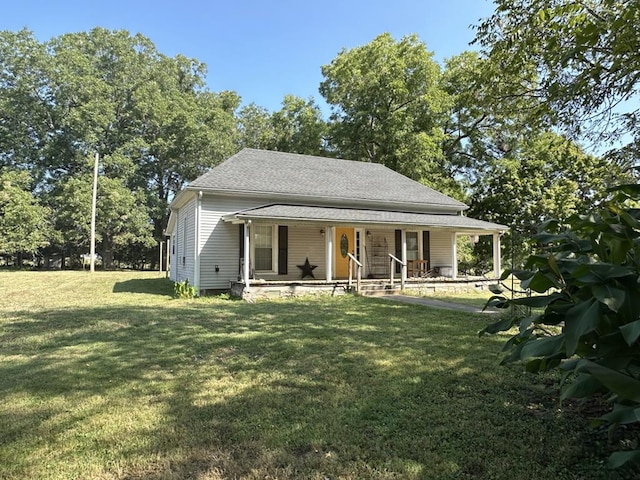 back of house with a porch, roof with shingles, and a lawn