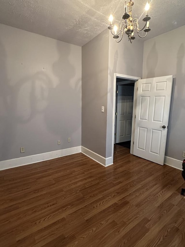 empty room with dark wood-style floors, baseboards, and a textured ceiling