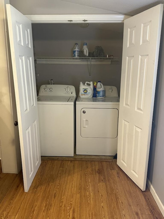 washroom featuring laundry area, baseboards, washer and clothes dryer, and wood finished floors