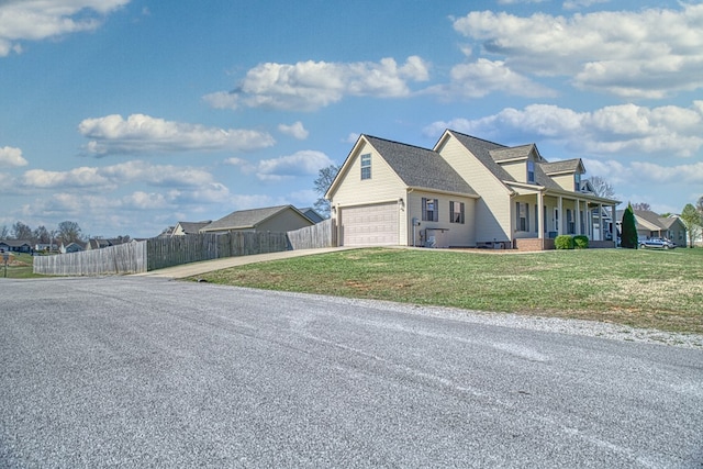 view of property exterior with fence, a garage, driveway, covered porch, and a yard