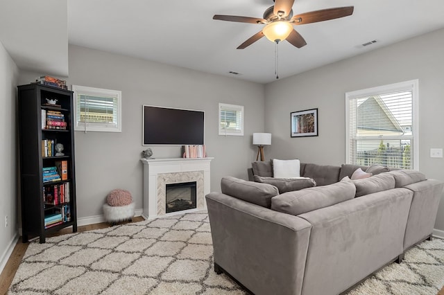 living area with visible vents, baseboards, ceiling fan, light wood-style floors, and a fireplace