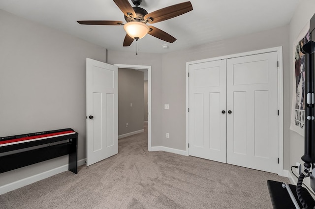 bedroom featuring a ceiling fan, a closet, light colored carpet, and baseboards