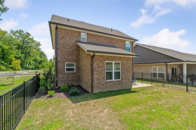 back of house with a yard, brick siding, a patio, and a fenced backyard