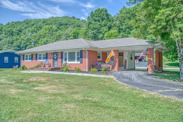 ranch-style house with driveway, brick siding, and a front yard