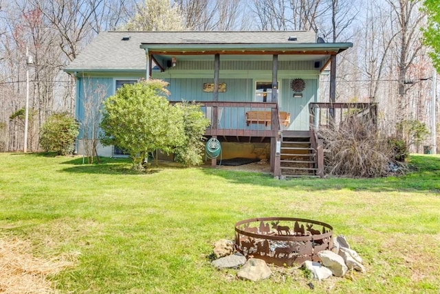 exterior space featuring a fire pit, roof with shingles, stairs, a wooden deck, and a front lawn