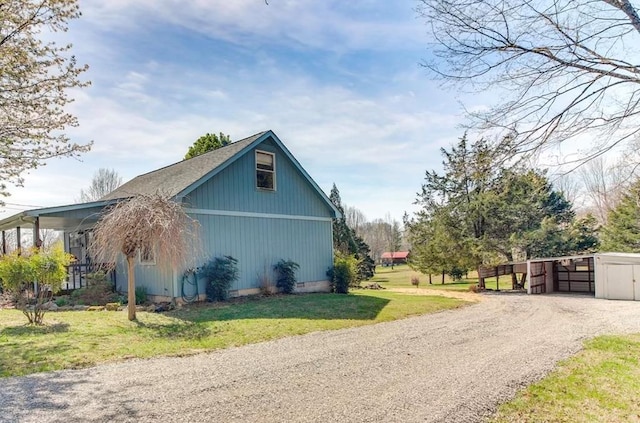 view of side of property featuring a yard, an outdoor structure, driveway, and a garage