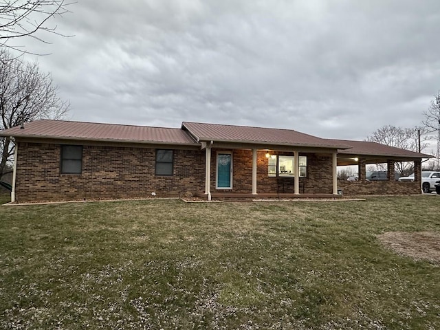 view of front facade with a front lawn, metal roof, a carport, and brick siding