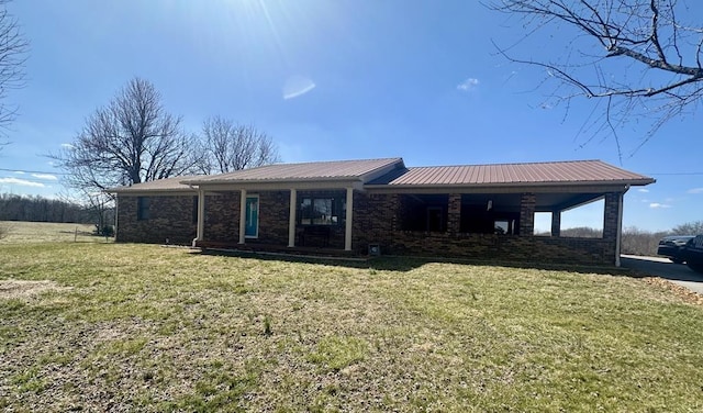 view of front of property featuring a front yard, brick siding, and metal roof