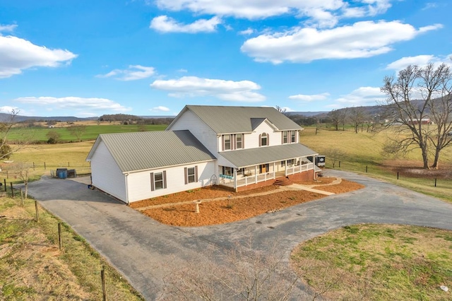 farmhouse with aphalt driveway, covered porch, a rural view, and metal roof