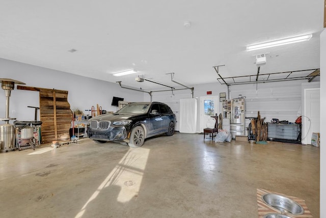 garage featuring freestanding refrigerator and a garage door opener