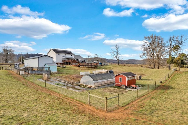 view of yard with an outbuilding, a deck with mountain view, a rural view, a greenhouse, and fence