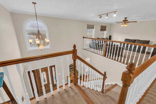 stairs with crown molding, baseboards, and ceiling fan with notable chandelier