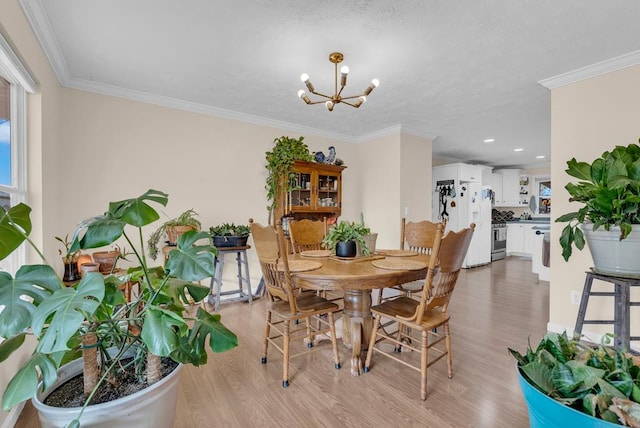 dining area with an inviting chandelier, crown molding, and light wood-style floors