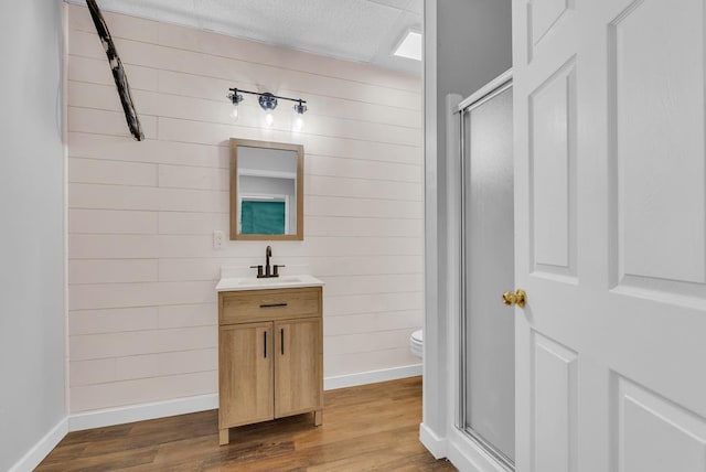 bathroom with toilet, wood finished floors, a shower stall, and vanity