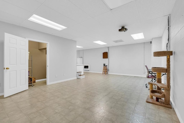 basement with a drop ceiling, baseboards, and tile patterned floors