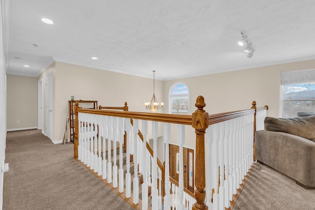 corridor featuring carpet floors, crown molding, a notable chandelier, and an upstairs landing