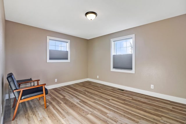 sitting room with wood finished floors, visible vents, and baseboards