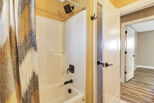 bathroom featuring wood finished floors, bathtub / shower combination, and baseboards