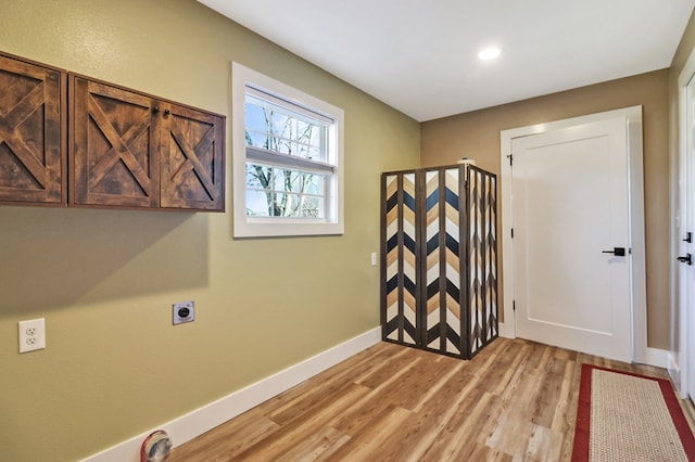 interior space featuring baseboards, hookup for an electric dryer, cabinet space, and light wood-style floors