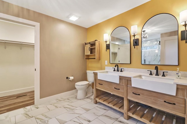 full bathroom with marble finish floor, a sink, baseboards, and double vanity