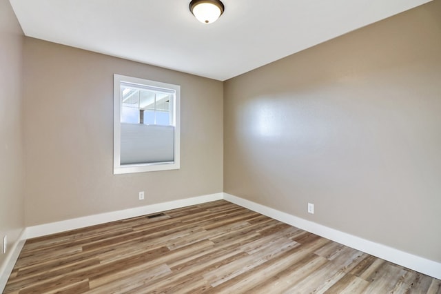 unfurnished room with light wood finished floors, visible vents, and baseboards