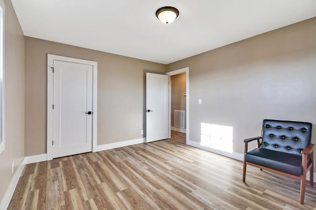 living area featuring light wood-style floors, visible vents, and baseboards