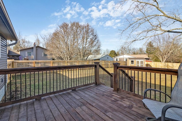 deck featuring a fenced backyard, a residential view, a lawn, and an outbuilding