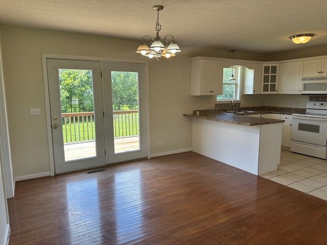 5514 Raven Xing, Baxter, TN 38544 - kitchen featuring white appliances, dark countertops, a peninsula, white cabinetry, and light wood-style floors