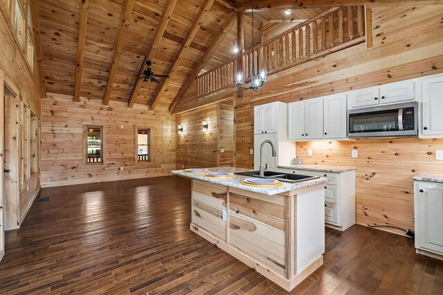106 Raccoon Ln, Jamestown, TN 38556 - kitchen with stainless steel microwave, wood walls, dark wood-style flooring, high vaulted ceiling, and white cabinets