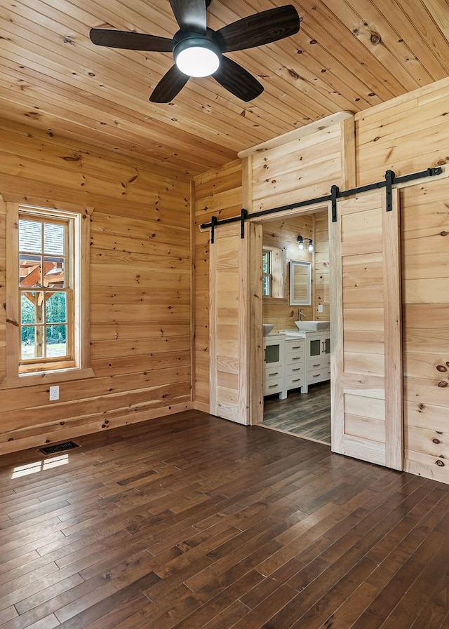 106 Raccoon Ln, Jamestown, TN 38556 - unfurnished bedroom featuring a barn door, wood walls, dark wood finished floors, wood ceiling, and ceiling fan