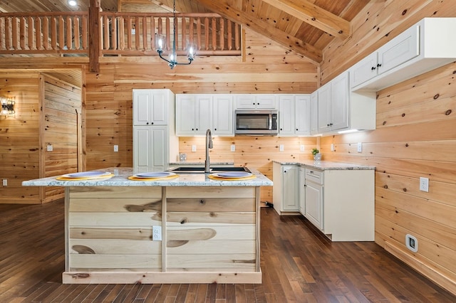 106 Raccoon Ln, Jamestown, TN 38556 - kitchen with stainless steel microwave, wood walls, dark wood finished floors, white cabinets, and decorative light fixtures