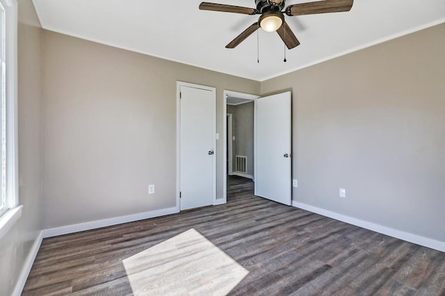 unfurnished bedroom with ceiling fan, dark wood-type flooring, visible vents, baseboards, and ornamental molding