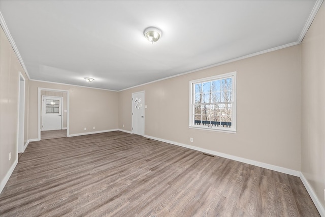 empty room with baseboards, wood finished floors, and crown molding