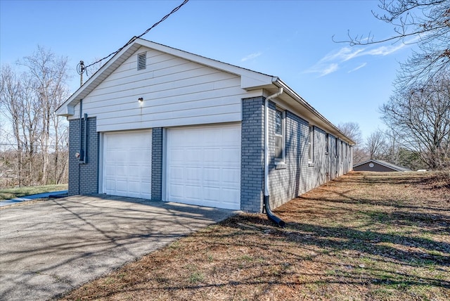 view of side of property featuring a garage and brick siding