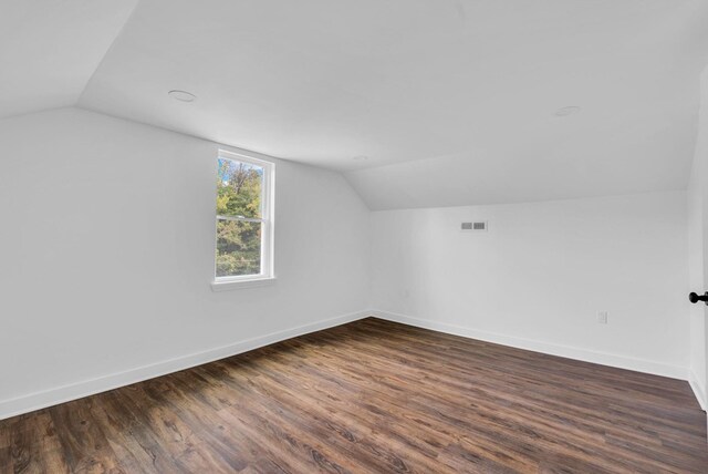 bonus room featuring lofted ceiling, dark wood-type flooring, visible vents, and baseboards