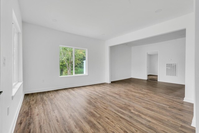 unfurnished room featuring dark wood-type flooring, visible vents, and baseboards