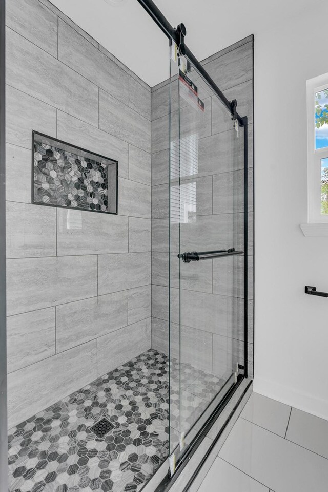 bathroom with a stall shower, tile patterned flooring, and baseboards